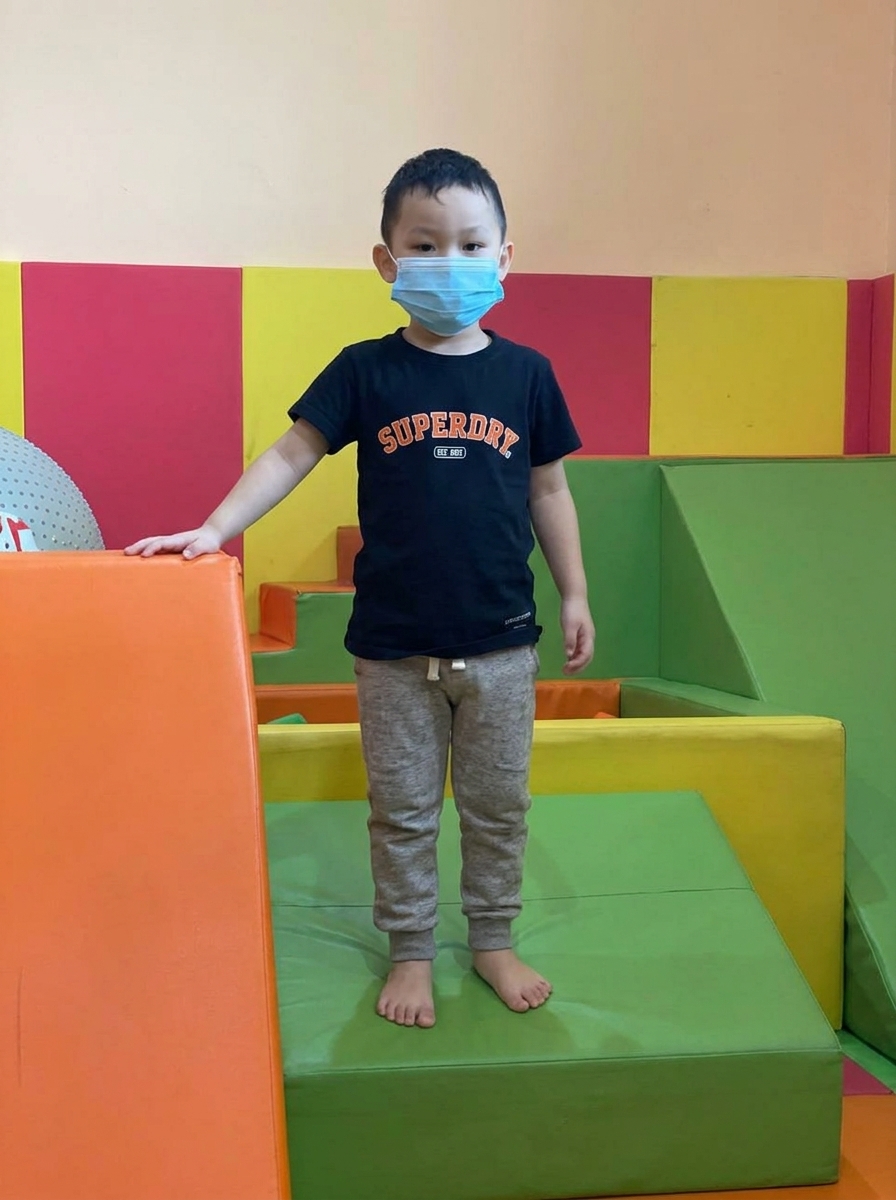 Anak laki-laki memakai masker di area bermain berbantalan