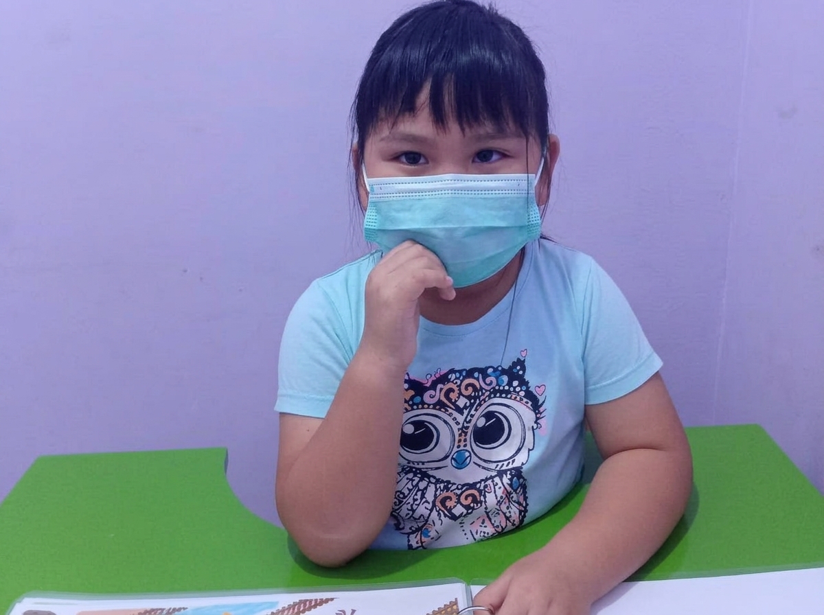 Anak perempuan memakai masker di kelas